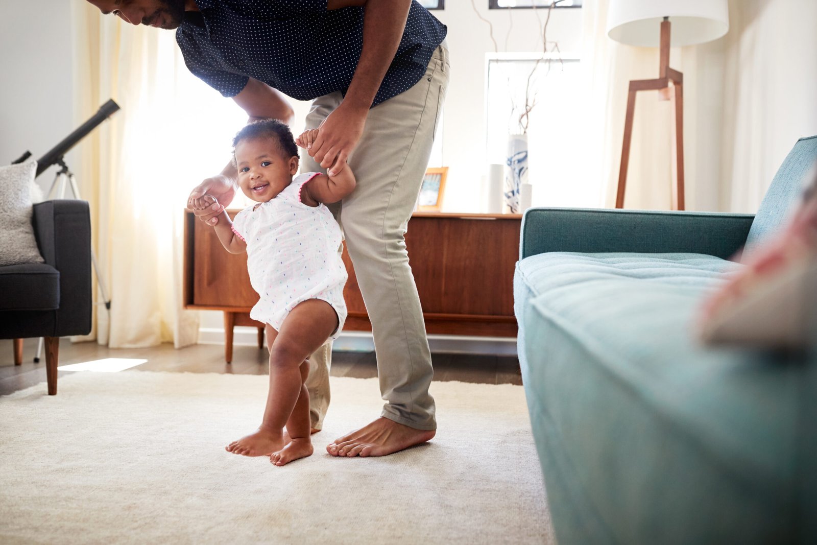 padre feliz con su hija enseñandole a dar sus primeros pasos en casa